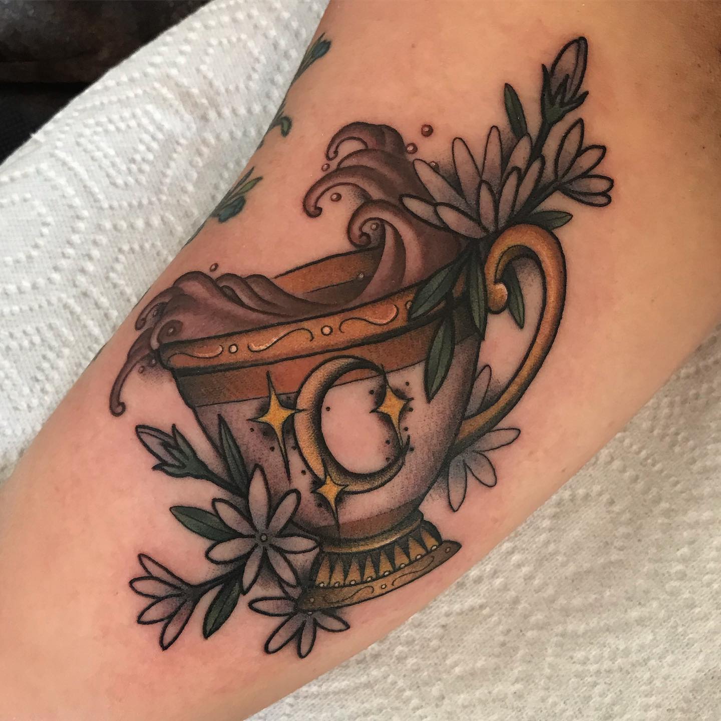 A gold teacup with jasmine flowers tattooed by Leah Westerlund